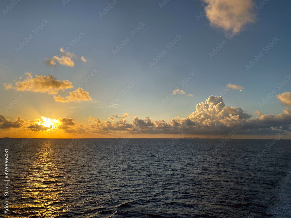 Seascape. Beautiful view of the horizon of the sea and sky with white clouds at sunset. Background of blue sky and ocean at sunset. Cadded shot, horizontal, free space. Rest and travel concept.