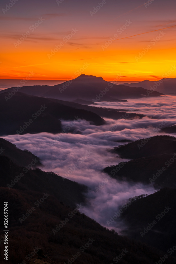 Fog between the mountains of the Basque country next to Mount Larrun at the golden hour of dawn