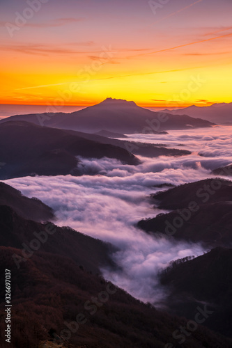 Fog between the mountains of the Basque country next to Mount Larrun at the golden hour of dawn. Vertical photo