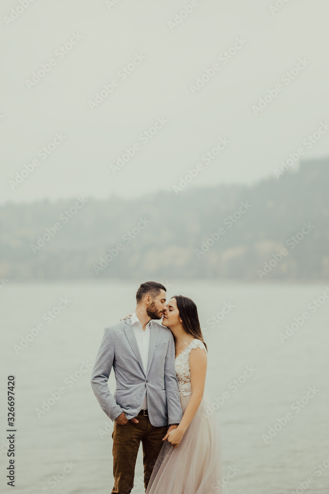 Beautiful happy bride and groom in boho style embracing at lake. Wedding.  Portrait of a gorgeous newlywed couple posing near the lake.