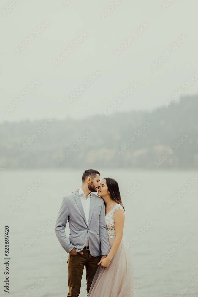 Beautiful happy bride and groom in boho style embracing at lake. Wedding. Portrait of a gorgeous newlywed couple posing near the lake. Beautiful happy bride and groom in boho style embracing at lake. Wedding. Portrait of a gorgeous newlywed couple posing near the lake.
