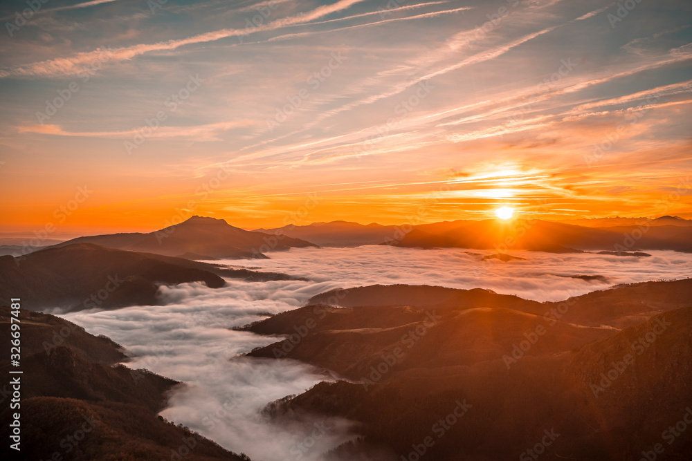 Sea of clouds between Mount Larrun and the village of Lesaka in an orange sunrise. Basque Country