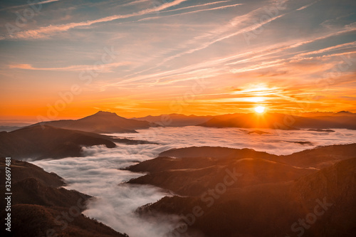 Sea of clouds between Mount Larrun and the village of Lesaka in an orange sunrise. Basque Country © unai