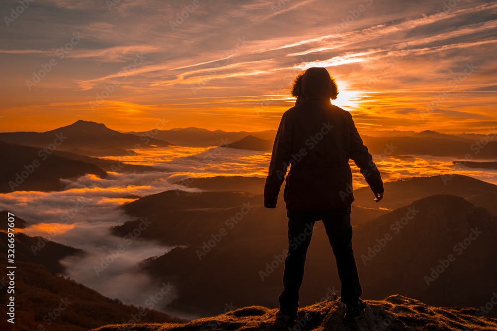 A young man enjoying the sunrise from Peñas de Aia with a sea of clouds below. Basque Country
