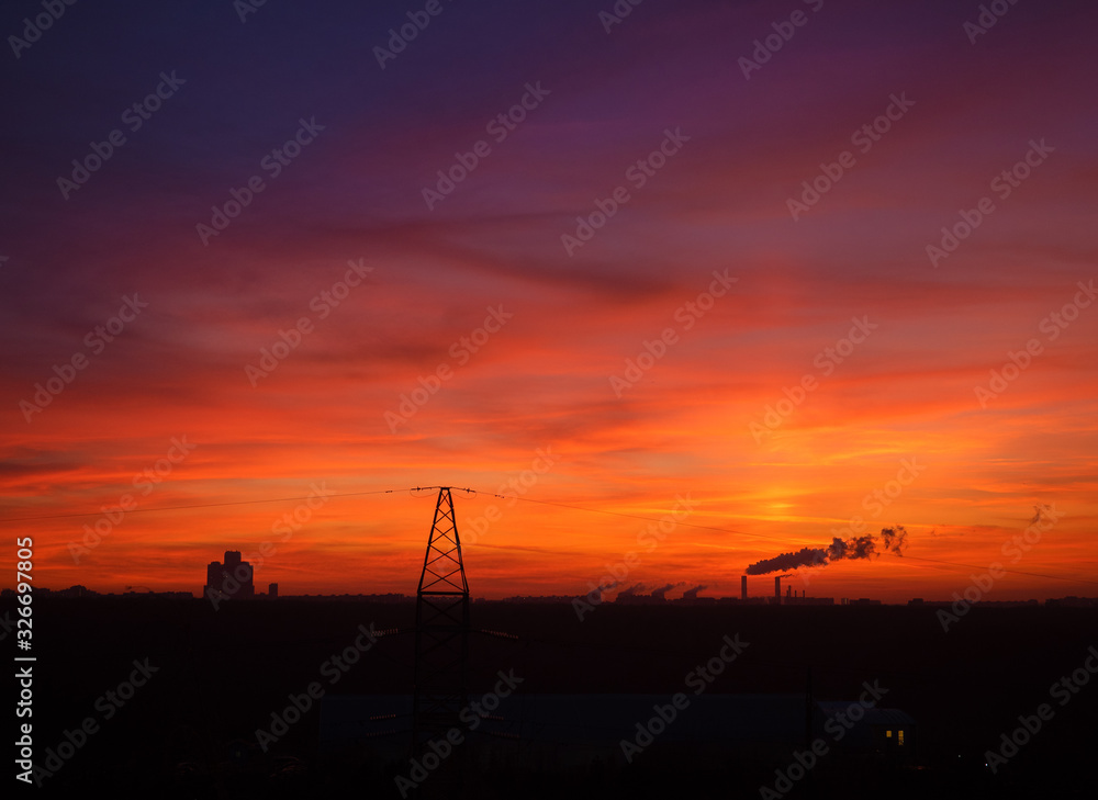Colorful cloudy epic sky on sunset over the panoramic  silhouette of the Moscow city skyline with transmission tower on foreground