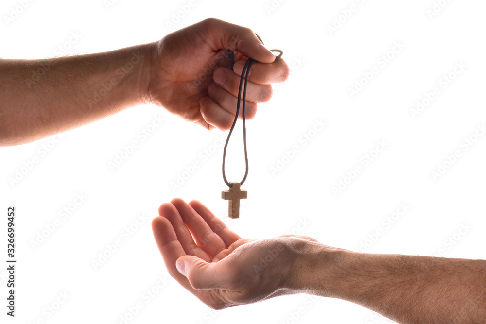 Hand giving another a pendant with cross symbol isolated white
