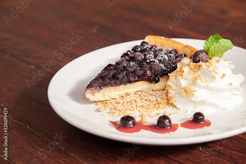 Sliced blueberry pie with fresh whipped cream and cookie crumble