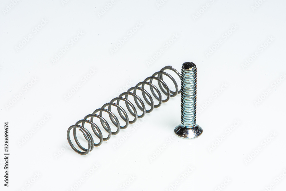 Detail of a small metal spring next to a small steel screw