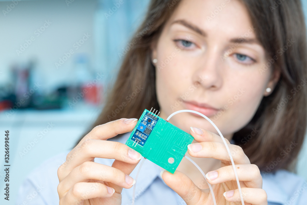 Young scientist woman in microbiological lab with lab-on-chip LOC microfluidic device Young scientist woman in microbiological lab with lab-on-chip LOC microfluidic device