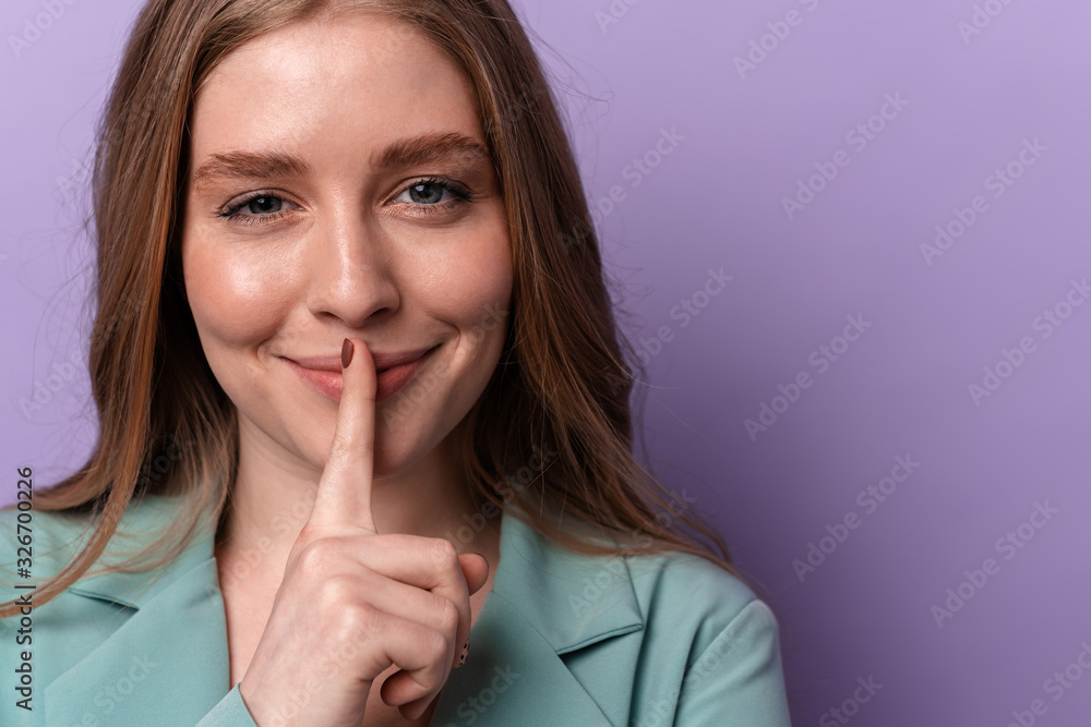 Fototapeta premium Smiling woman showing silence gesture