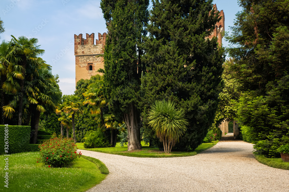 Scenic landscape with beautiful garden in front of ruins of medieval castle in Veneto region, Italy. Sunny day in italian countryside. Travel tourism destination Italy