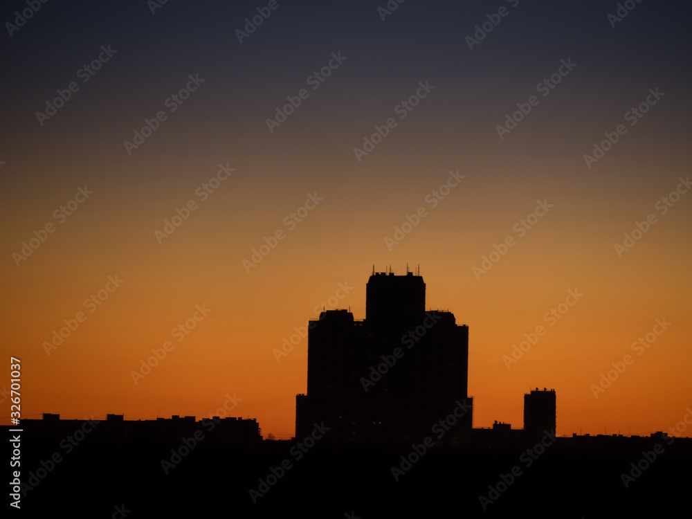 Skyscraper tower silhouette over dark forest on sunset and clear sky as background. Sunny weather (Moscow city, Russia)
