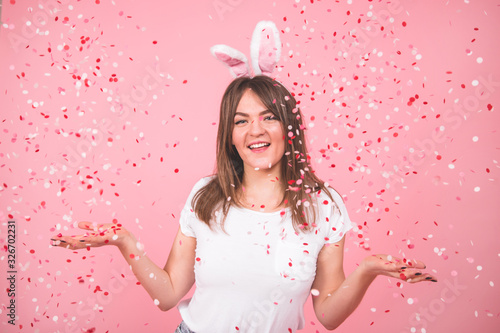 Holiday concept. Beautiful smiling girl holding confetti in hands isolated over pink background