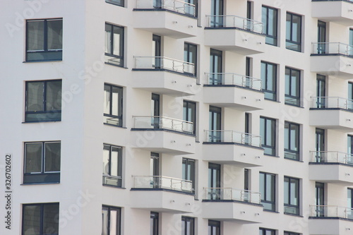 Parts of the modern facade of apartment buildings made of glass and concrete with highlights on the windows in beige colors. Trends in buildings