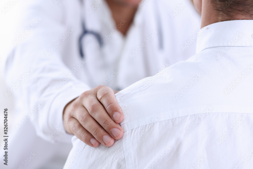 Friendly male doctor hold patient shoulder in office during reception. Examination result, positive test, calm down, promise and cheer up, grief and suffer, treatment, condolence, ethics concept Friendly male doctor hold patient shoulder in office during reception. Examination result, positive test, calm down, promise and cheer up, grief and suffer, treatment, condolence, ethics concept