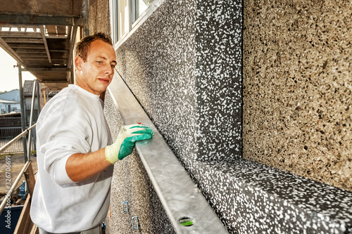 Εκτύπωση καμβά A craftsman installs polystyrene panels for thermal insulation on a house facade