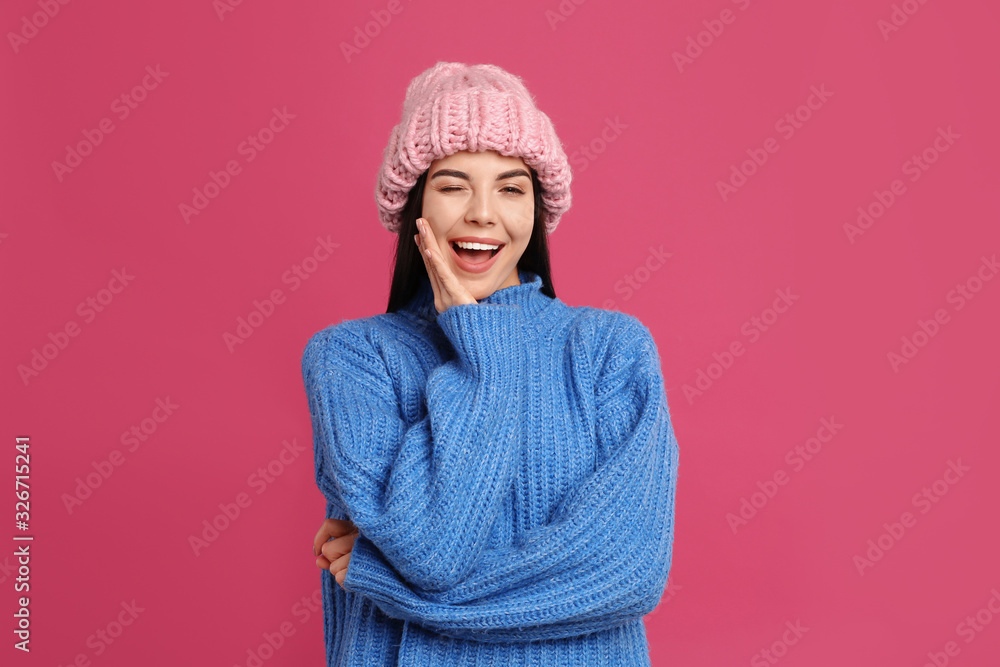 Young woman wearing warm sweater and hat on crimson background. Winter season Young woman wearing warm sweater and hat on crimson background. Winter season
