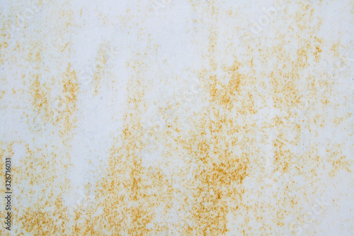 White old metal sheet with small spots of rust. The rust comes out through the paint with non-uniform spots. White background with brown corrosion.