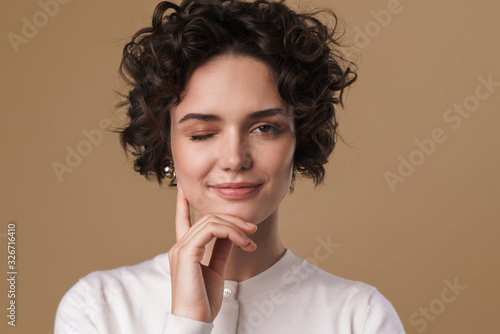 Image of pleased attractive woman winking and looking at camera