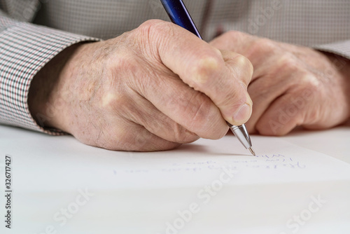 mature man writes letter on paper at white table in room