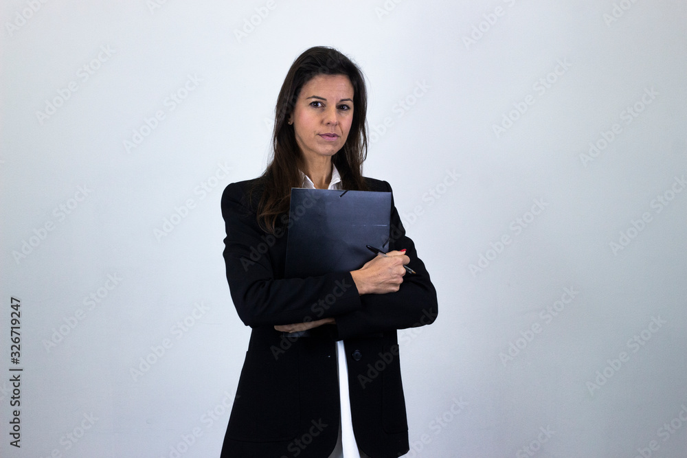 Portrait of fashionable caucasian bussiness woman with a folder in her hands, isolated on gray background studio shot, white shirt and black jacket, dark air. Place for your text in copy space. Portrait of fashionable caucasian bussiness woman with a folder in her hands, isolated on gray background studio shot, white shirt and black jacket, dark air. Place for your text in copy space.