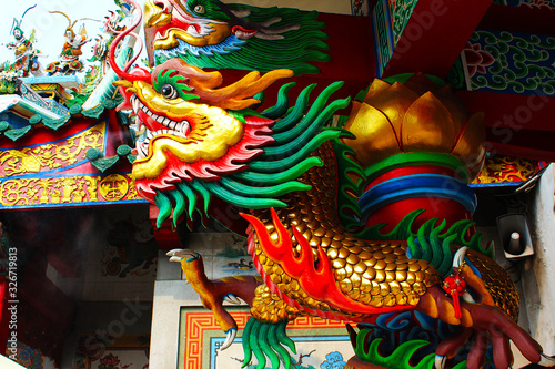 A golden dragon statue wrapped around a red pillar