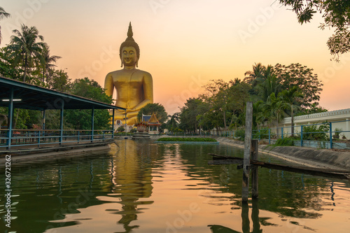 .scenery sunset behind the great Buddha of Thailand at wat Muang Ang Thong Thailand. .The largest Buddha statue in the world can be seen from afar surrounded by rice fields. photo