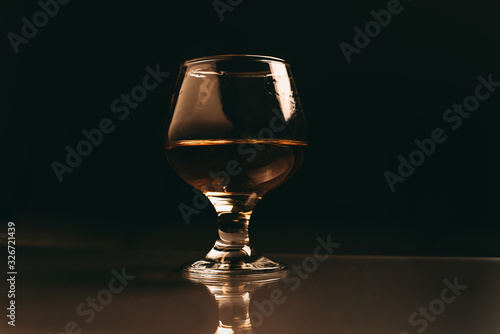glass of cognac on a dark background with a warm filter close up