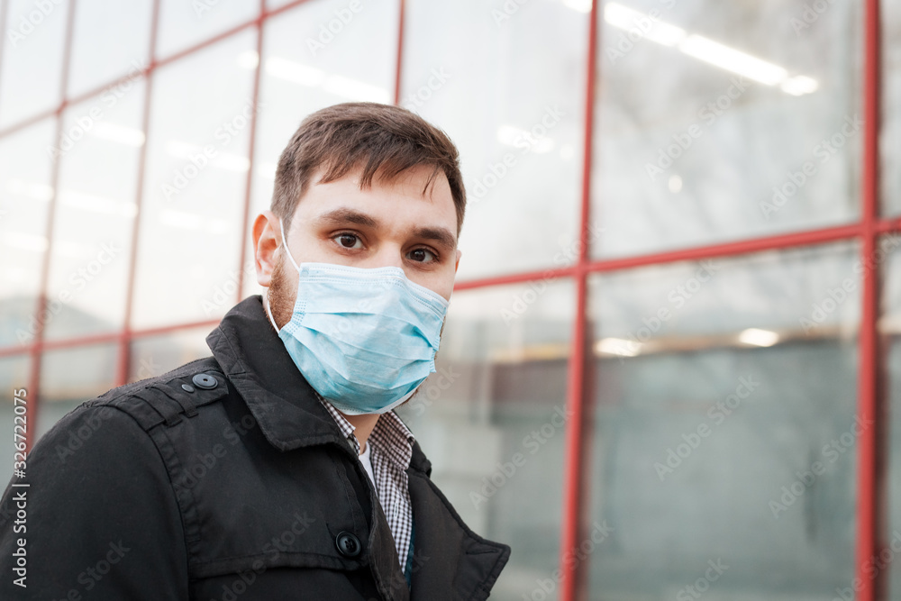 European coronavirus. Portrait of caucasian man wearing facial hygienic mask, respiratory protection mask outdoors. Virus, coronavirus protection, air pollution, ecology, environmental awareness.