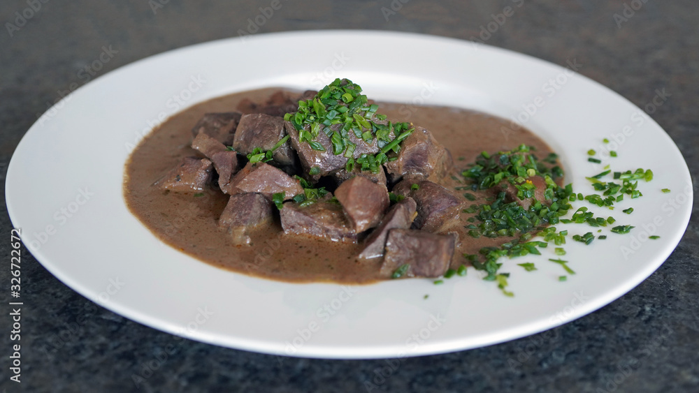 ready to eat, liver, heart and kidneys in sour sauce with chives on a white plate ready to eat, liver, heart and kidneys in sour sauce with chives on a white plate