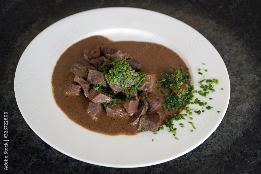 ready to eat, liver, heart and kidneys in sour sauce with chives on a white plate ready to eat, liver, heart and kidneys in sour sauce with chives on a white plate