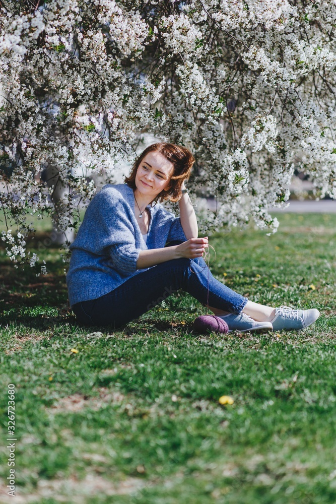 I can create anywhere. Woman knitting outside in the garden. Cherry tree is in blossom. Creativity and freedom concept I can create anywhere. Woman knitting outside in the garden. Cherry tree is in blossom. Creativity and freedom concept