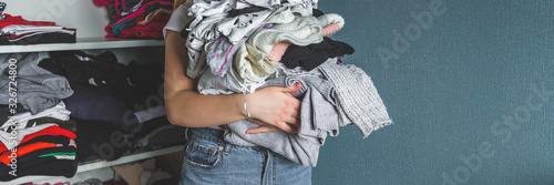 Fast fashion, the girl puts things in order in the closet. A bunch of colorful clothes. The concept of processing, second hand, eco, minimalism, consumption of goods. photo