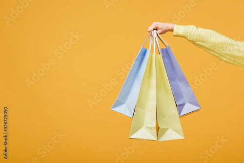 cropped view of young woman holding shopping bags isolated on yellow