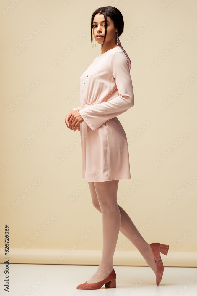 beautiful african american girl in dress standing on beige beautiful african american girl in dress standing on beige