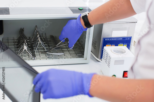 Specialist takes out manicure tools from an ultraviolet sterilizer photo