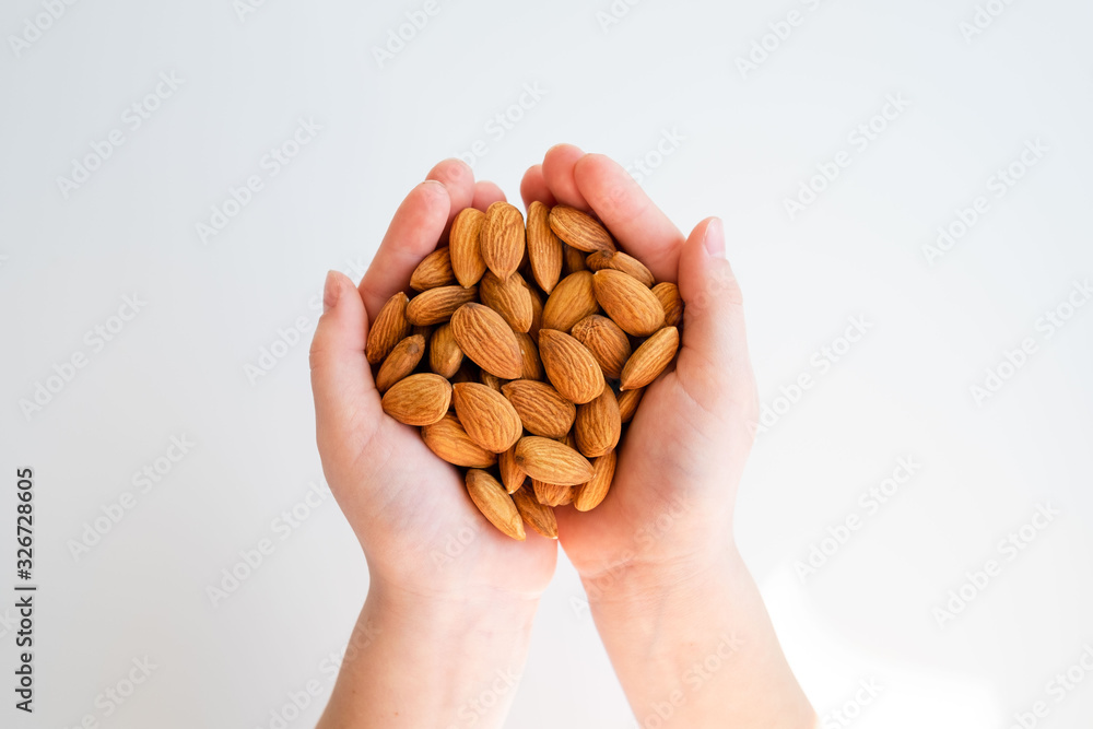 Healthy eating, dieting, vegetarian food concept. Close up of kid hands holding peeled almond on white background