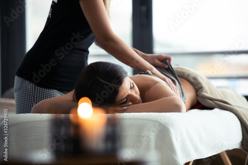 Young woman removing the chocolate cream with towel to a pretty woman on the spa center.