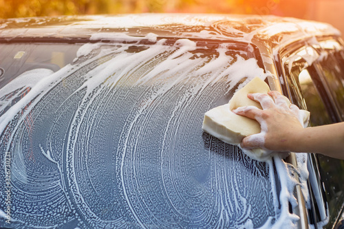 A woman washes the windshield of a car