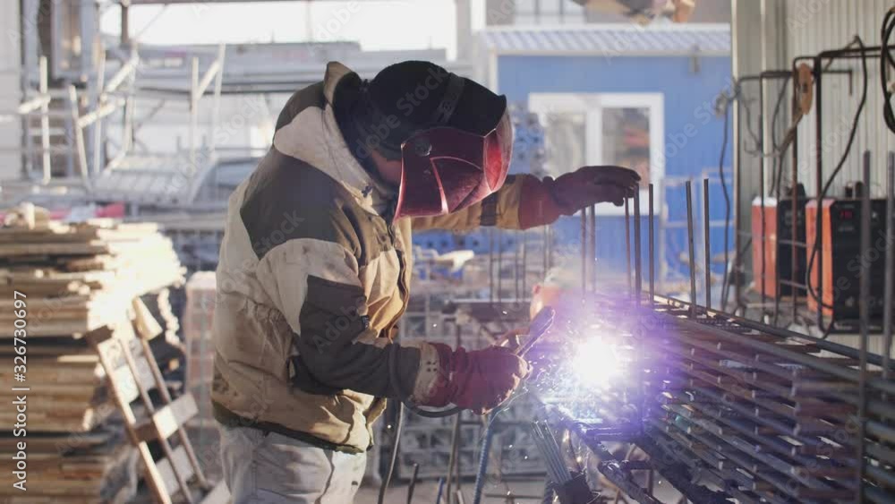 Wedler. Welder works at a construction site. Smoke from welding. Electric arc welding. Wedler. Welder works at a construction site. Smoke from welding. Electric arc welding.