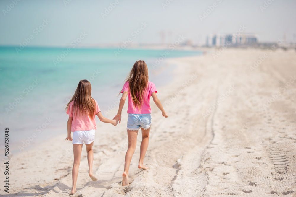 Little happy funny girls have a lot of fun at tropical beach playing together. Sunny day with rain in the sea Little happy funny girls have a lot of fun at tropical beach playing together. Sunny day with rain in the sea