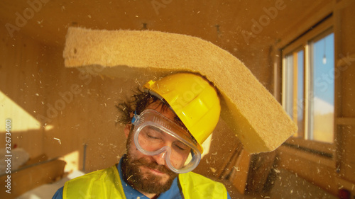 PORTRAIT: Funny shot of a smiling builder getting hit with a thick piece of foam photo