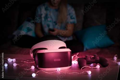 VR virtual reality. Girl wants to get experience using glasses of a VR headset. Amazing emotions, cool rest, reboot. Virtual reality glasses lie in neon lights. Concept of visual reality