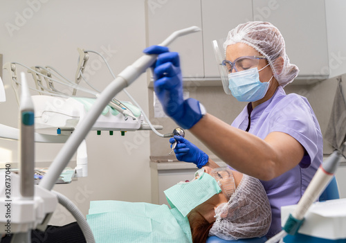 The dentist using specialized tools treats caries in the patient’s oral cavity using new technologies in dentistry.