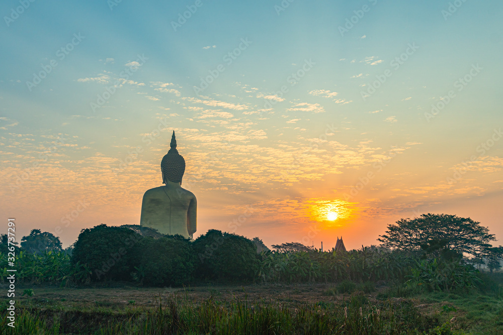 scenery sunrise in front of the great Buddha of Thailand at wat Muang Ang Thong Thailand. .The largest Buddha statue in the world Can be seen from afar Surrounded by rice fields.
