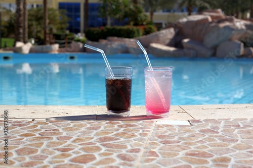 Two cocktail glasses by a blue water