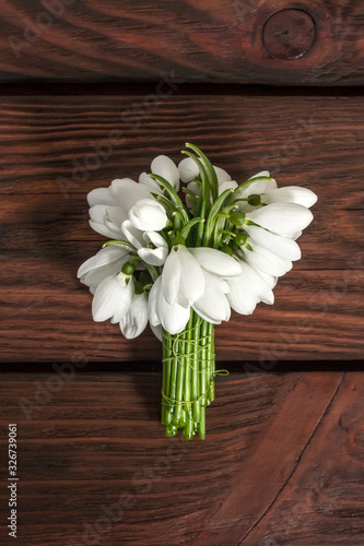 Fototapeta Naklejka Na Ścianę i Meble -  Beautiful white snowdrops Galanthus nivalis on a wooden background with bokeh . Top view, flat lay