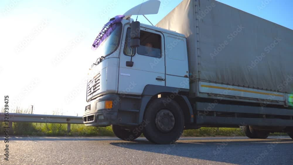 Truck driving on a highway. Lorry rides through the countryside with sunset at background. Bottom Side view Slow motion Close up Truck driving on a highway. Lorry rides through the countryside with sunset at background. Bottom Side view Slow motion Close up