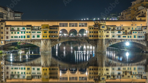Famous Ponte Vecchio bridge timelapse over the Arno river in Florence, Italy, lit up at night photo