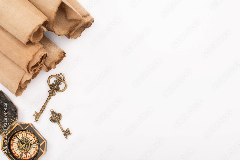 Fototapeta premium top view of vintage keys, compass and rolled aged paper isolated on white